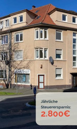 Mehrfamilienhaus mit rotem Dach, beige Fassade.